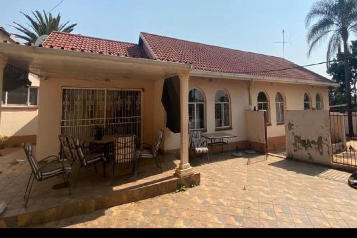 Rear view of the house featuring a covered patio area with tiled flooring and arched window detailing.