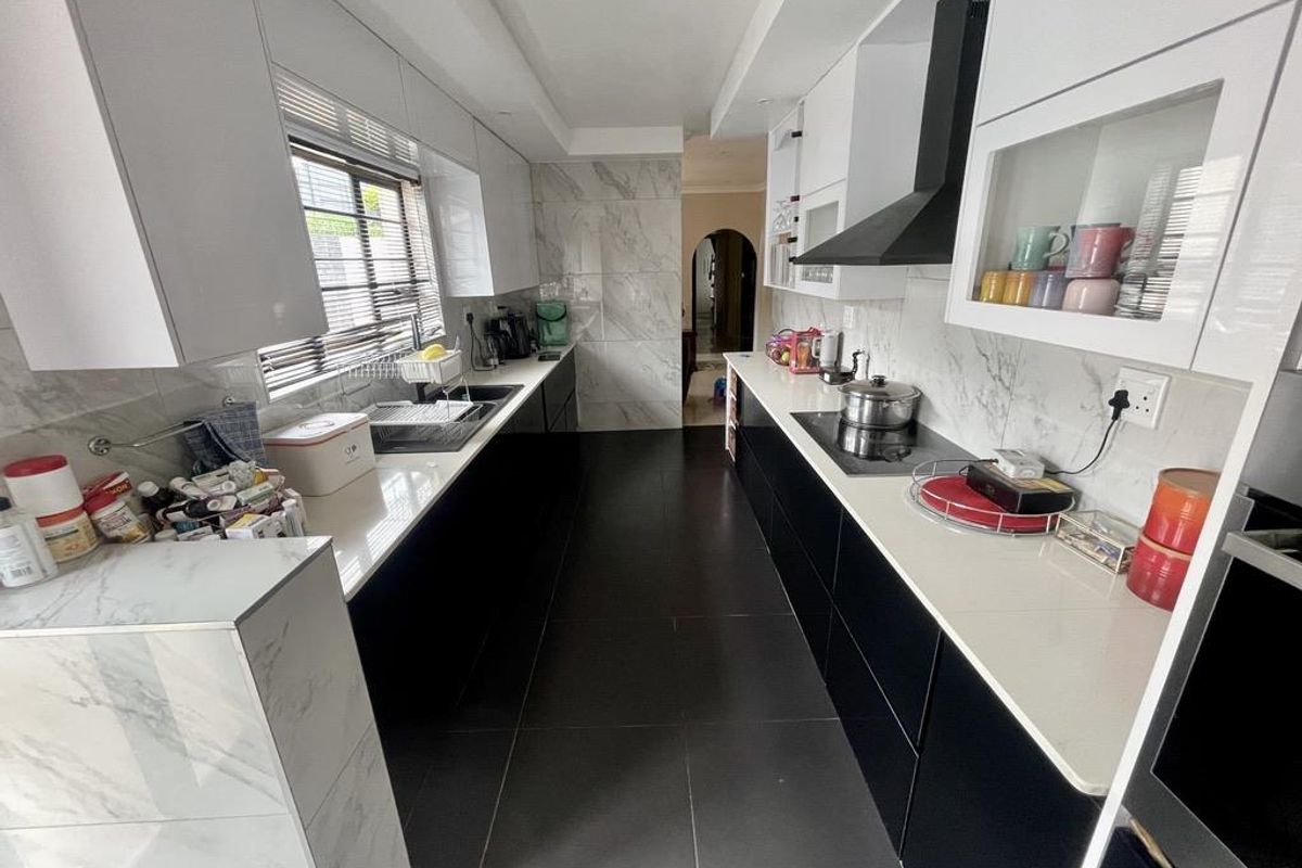 Modern galley-style kitchen featuring high-contrast black and white cabinetry, marble-look splashbacks, stone countertops, and integrated appliances.