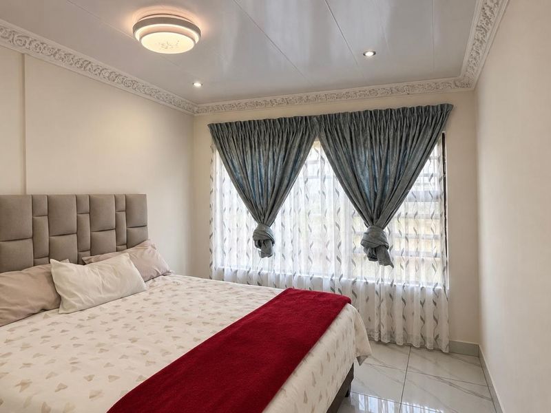 A well-maintained bedroom featuring decorative crown molding, recessed ceiling lighting, and modern tiled flooring.