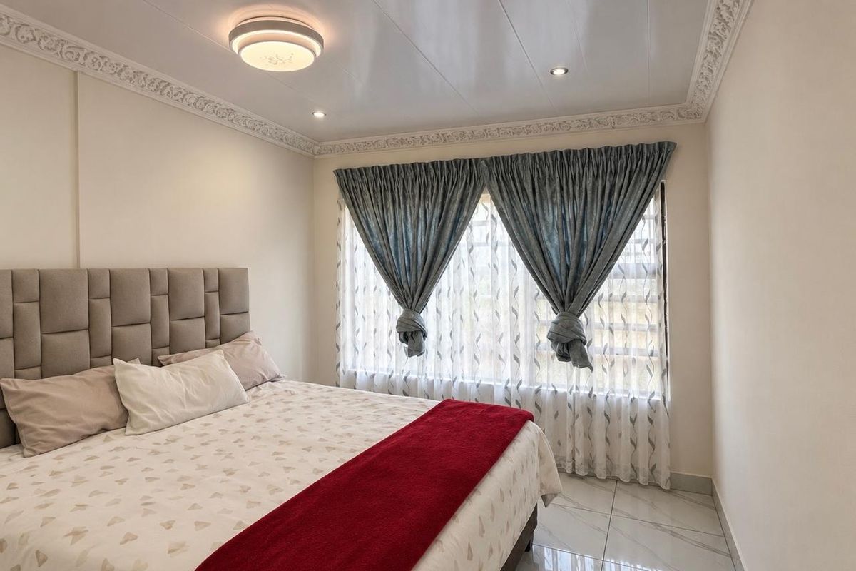 A well-maintained bedroom featuring decorative crown molding, recessed ceiling lighting, and modern tiled flooring.