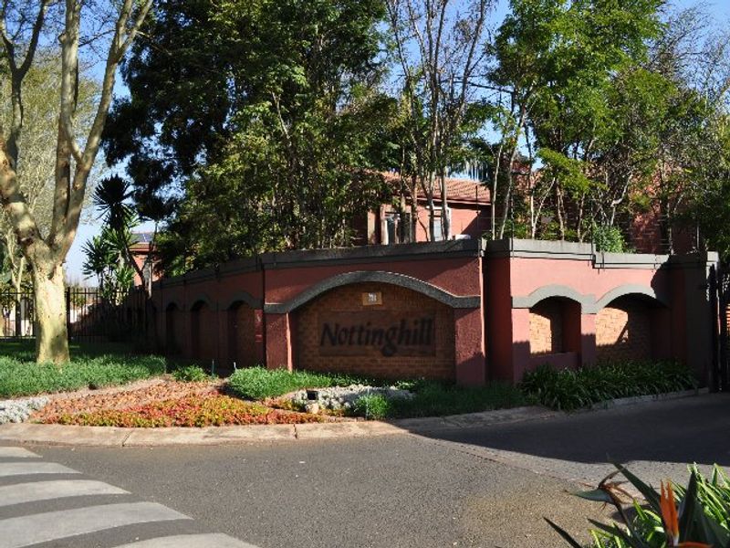 The front entrance and perimeter wall of the Nottinghill residential complex, featuring established landscaping and a paved driveway.