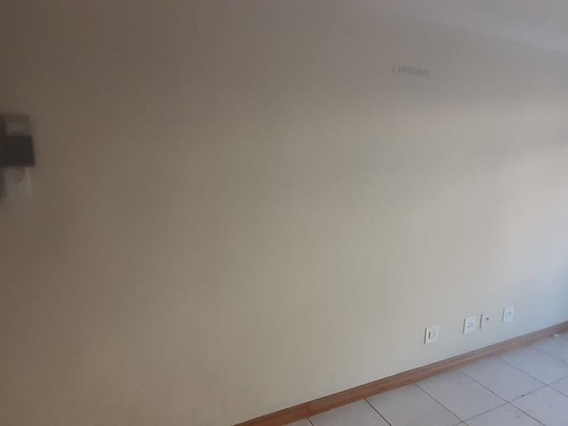 An empty living area featuring tiled flooring, an intercom system, and neutral walls, providing a blank canvas for personalization.