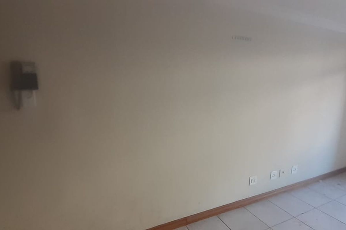 An empty living area featuring tiled flooring, an intercom system, and neutral walls, providing a blank canvas for personalization.