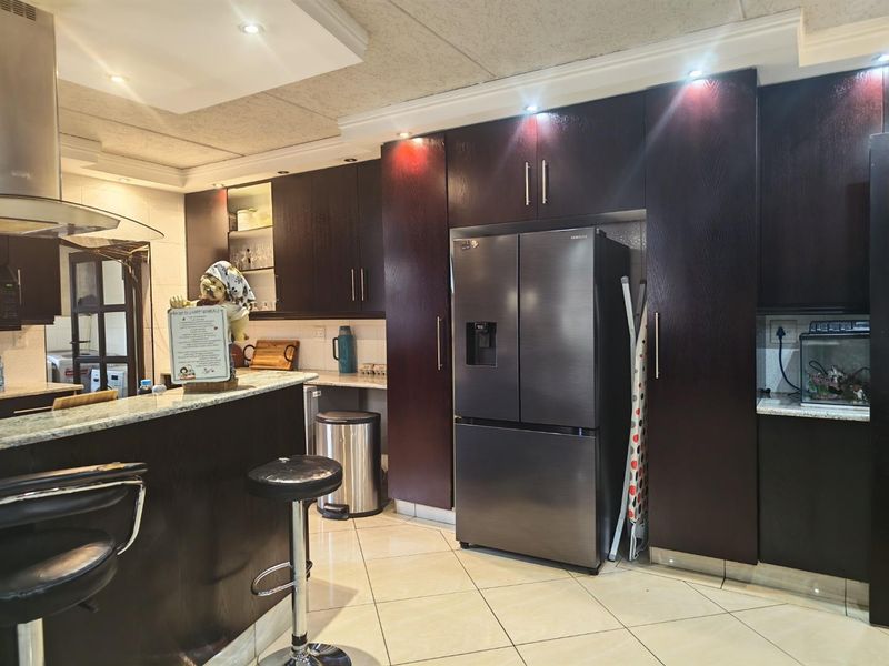 A well-appointed kitchen featuring dark wood cabinetry, granite countertops, a breakfast bar, and modern recessed lighting, offering a functional and stylish cooking space.