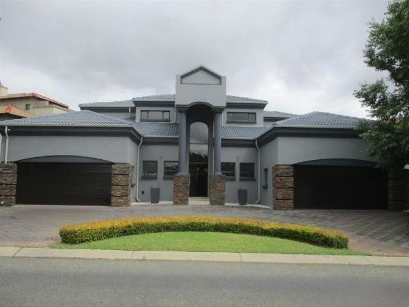 Modern double-story residence featuring a symmetrical facade, stone-clad pillars, a paved driveway, and a double garage.