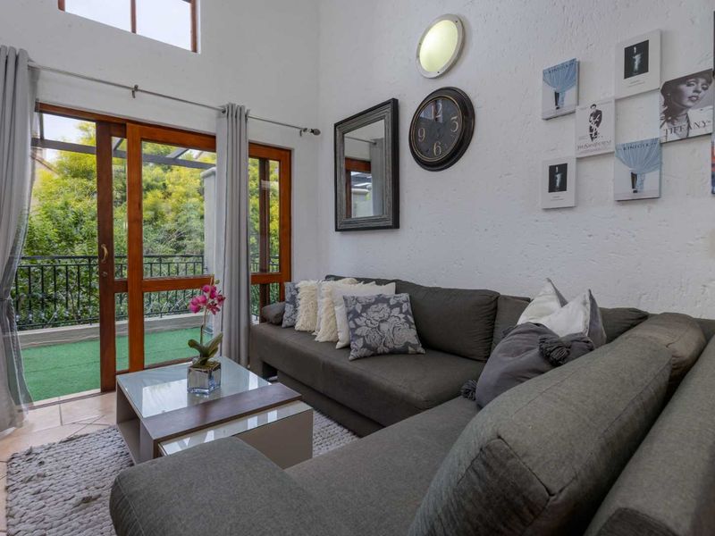 A bright living room featuring high ceilings, tiled flooring, and large sliding glass doors that provide direct access to an outdoor balcony.