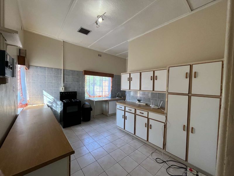 A functional kitchen featuring built-in cabinetry, tiled flooring, a tiled backsplash, and a freestanding stove, offering potential for modernization and cosmetic updates.