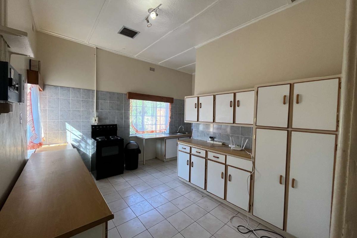 A functional kitchen featuring built-in cabinetry, tiled flooring, a tiled backsplash, and a freestanding stove, offering potential for modernization and cosmetic updates.
