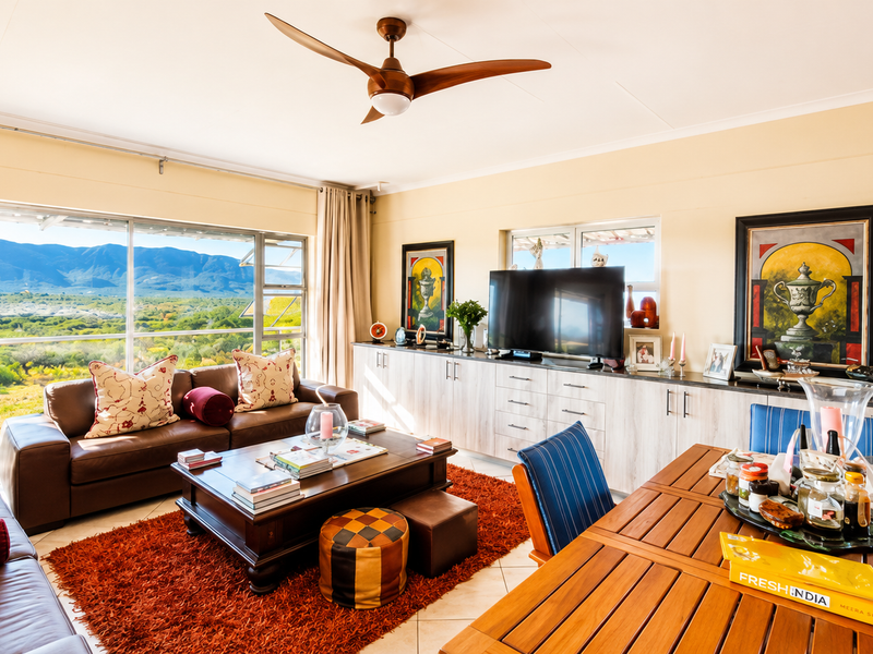 Spacious open-plan living and dining area featuring built-in cabinetry, a ceiling fan, and large windows offering expansive mountain and landscape views.