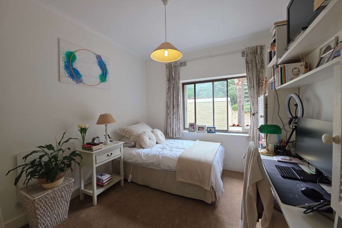 A functional bedroom featuring built-in shelving, carpeted flooring, and a window providing natural light.