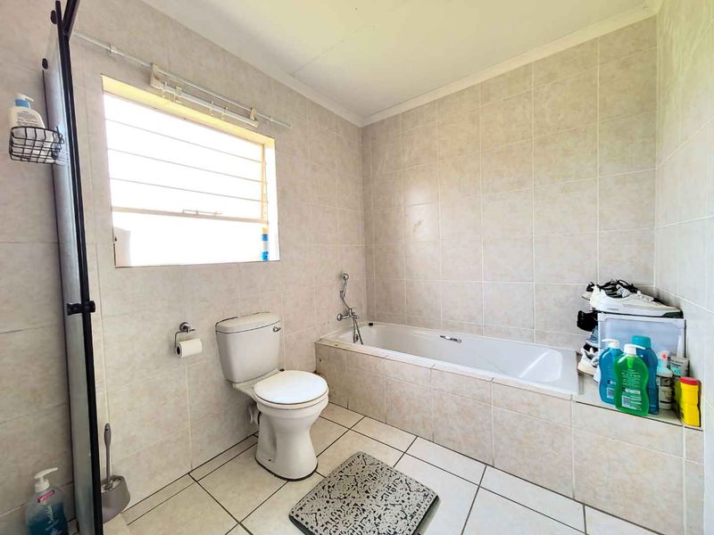 A functional bathroom featuring tiled walls and flooring, a built-in bathtub, and a toilet, providing a clean and practical space.