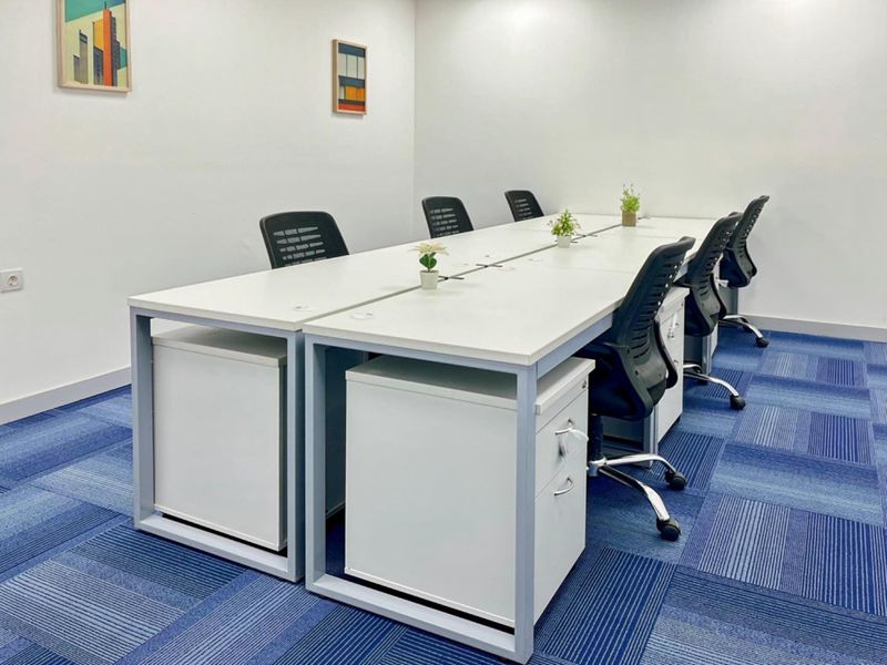 A clean and functional office space featuring blue patterned carpeting and white walls, suitable for a professional work environment.