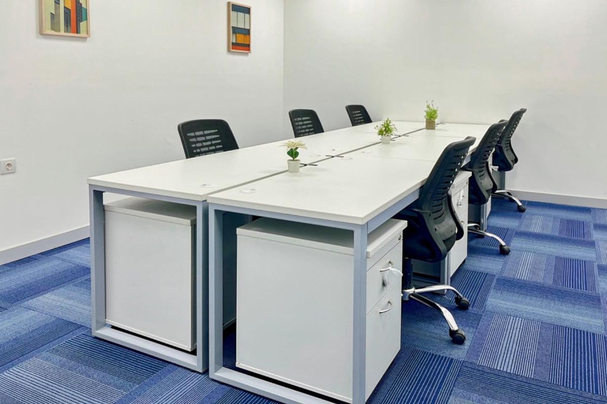 A clean and functional office space featuring blue patterned carpeting and white walls, suitable for a professional work environment.