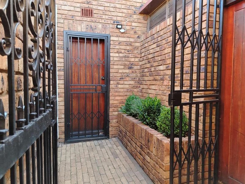 A secure entrance area featuring a brick facade, a sturdy security gate, and a built-in brick planter box.