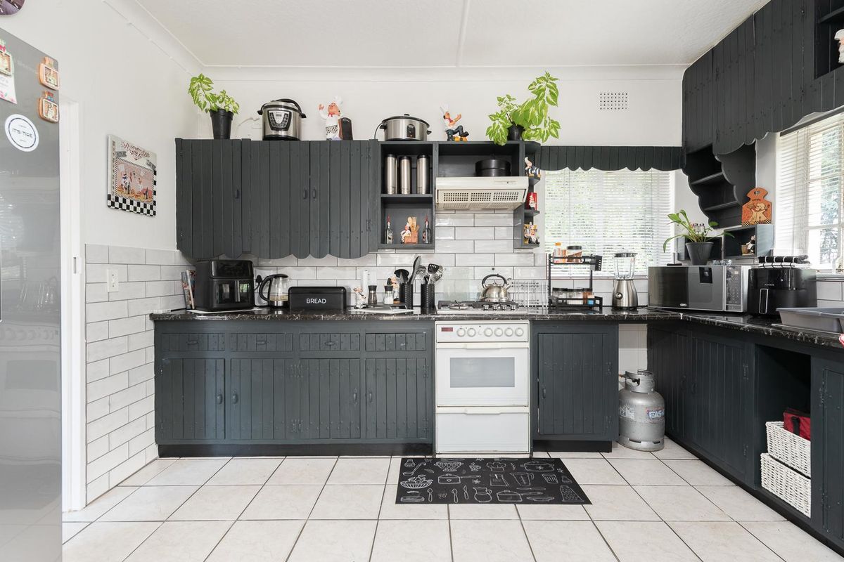 A functional kitchen featuring dark painted cabinetry, subway tile backsplash, built-in oven with gas hob, and tiled flooring.