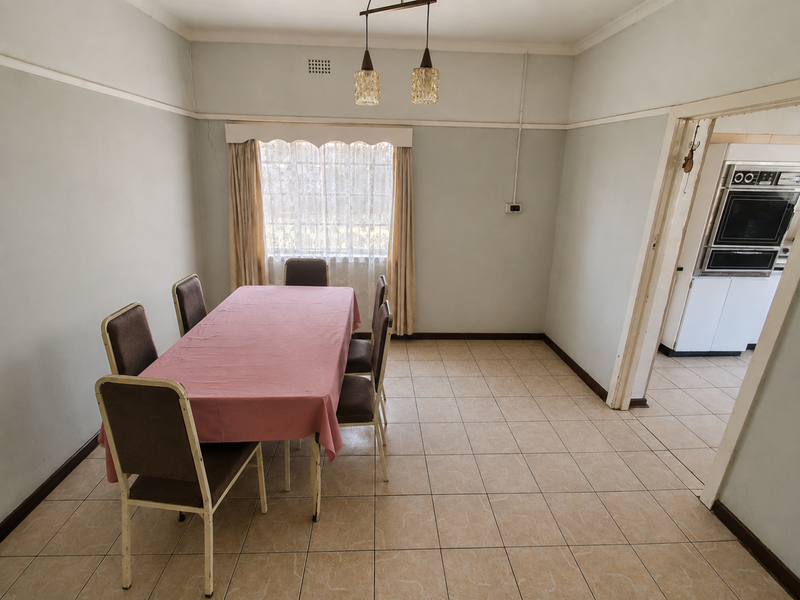 A dining room featuring tiled flooring, picture rails, and pendant lighting, with an adjacent view into the kitchen area containing a built-in wall oven.