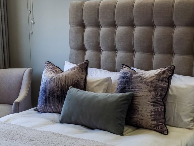 A well-maintained bedroom featuring a tufted headboard and venetian blinds, offering a comfortable and neutral living space.