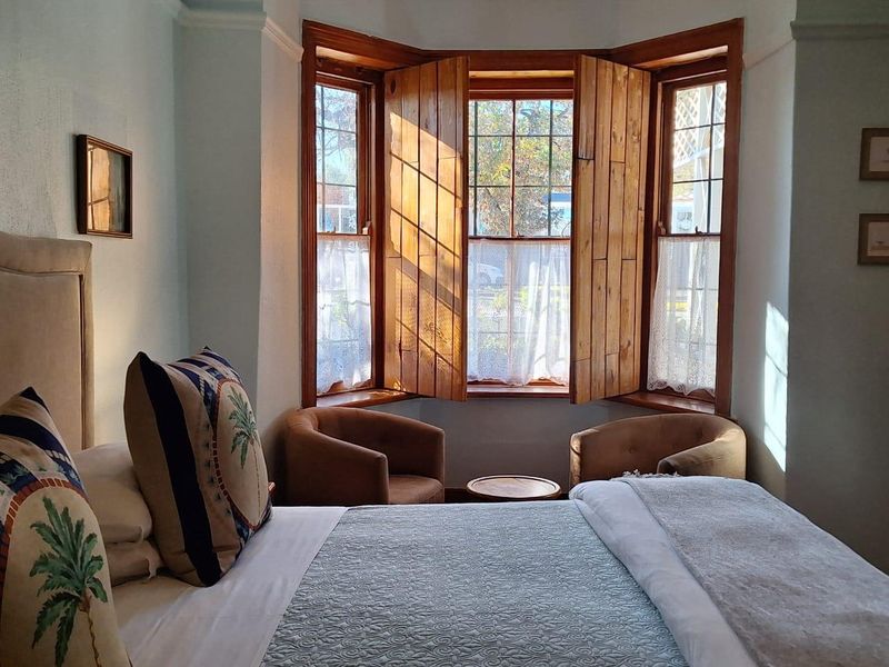 A cozy bedroom featuring a classic bay window with natural wooden shutters, providing ample natural light and a charming architectural focal point.