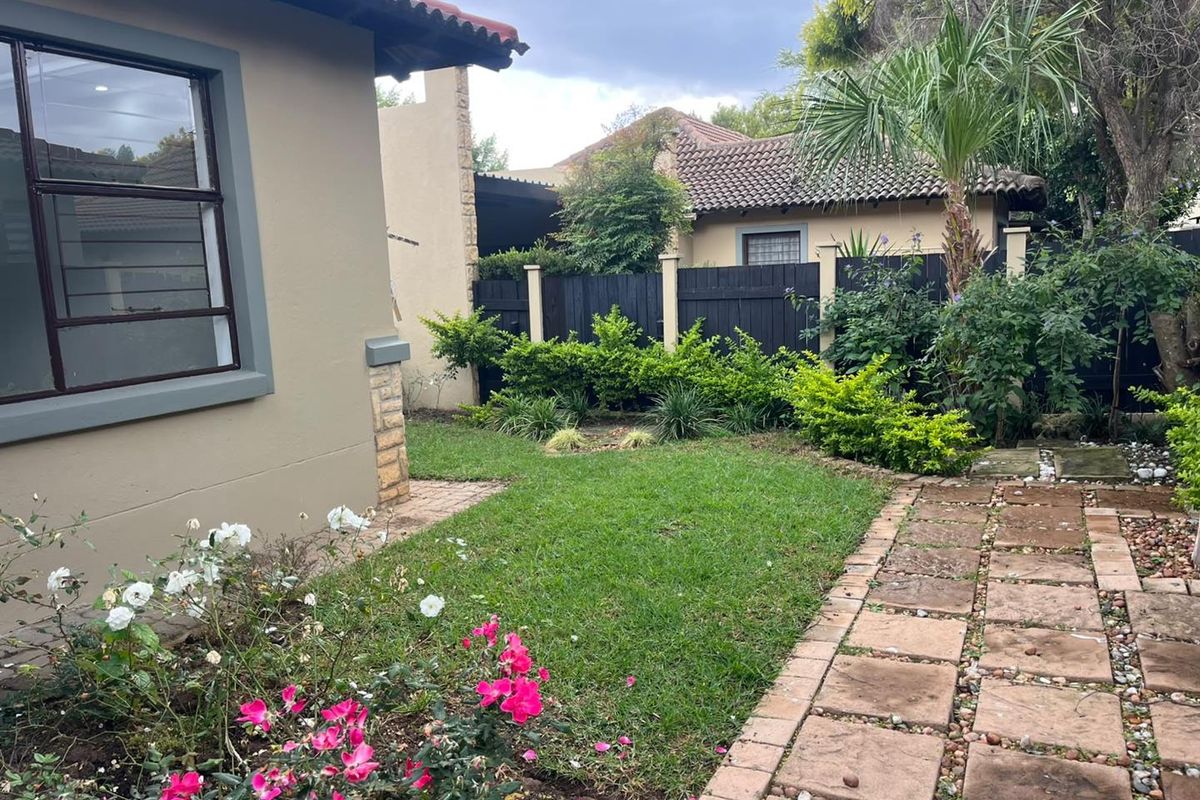A private rear garden featuring a small lawn, paved walkway, and established perimeter fencing with mature landscaping.