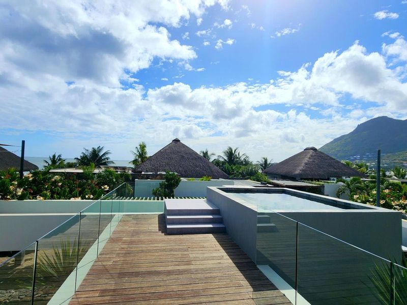 A modern rooftop terrace featuring a private plunge pool, timber decking, and glass balustrades with scenic mountain and coastal views.