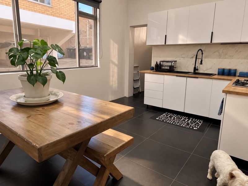Modern kitchen featuring white cabinetry, wooden countertops, stone-look backsplash, and dark floor tiles, offering a clean and functional cooking space.