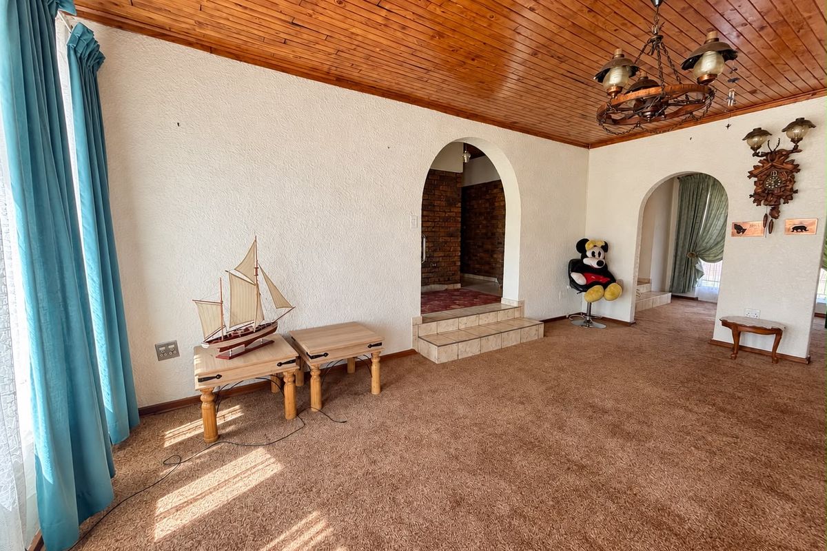 Spacious living area featuring a timber-clad ceiling, arched architectural transitions, and a raised tiled step leading to an adjacent room with exposed brickwork.