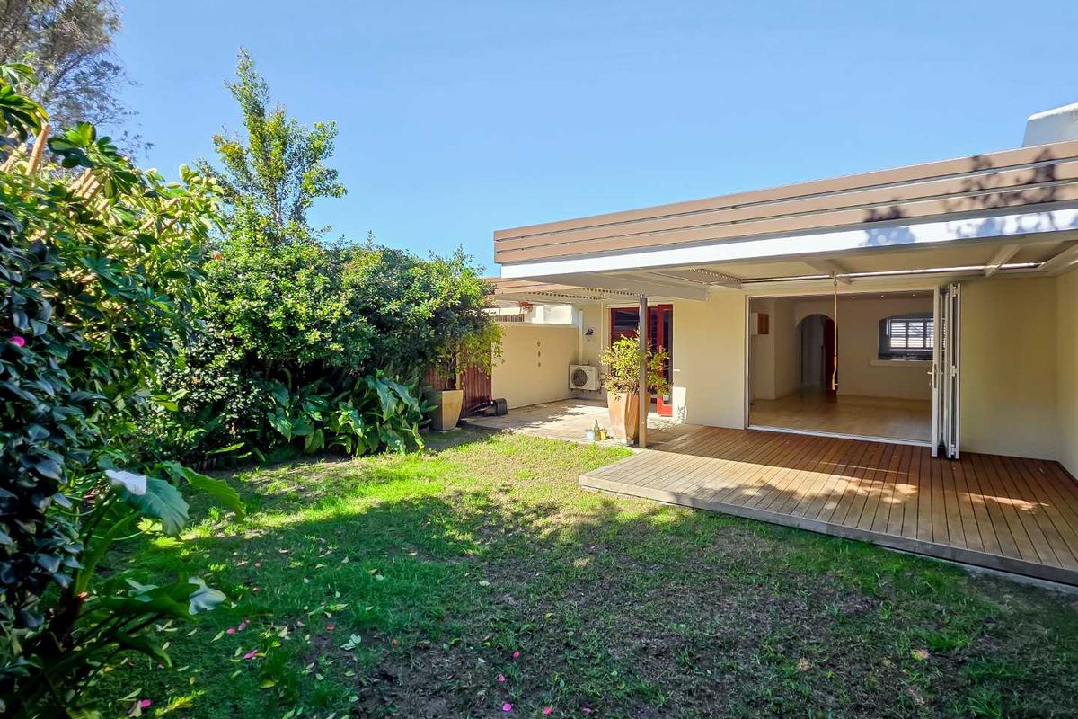 Rear garden featuring a timber deck, covered patio area, and bi-fold doors providing seamless indoor-outdoor flow.