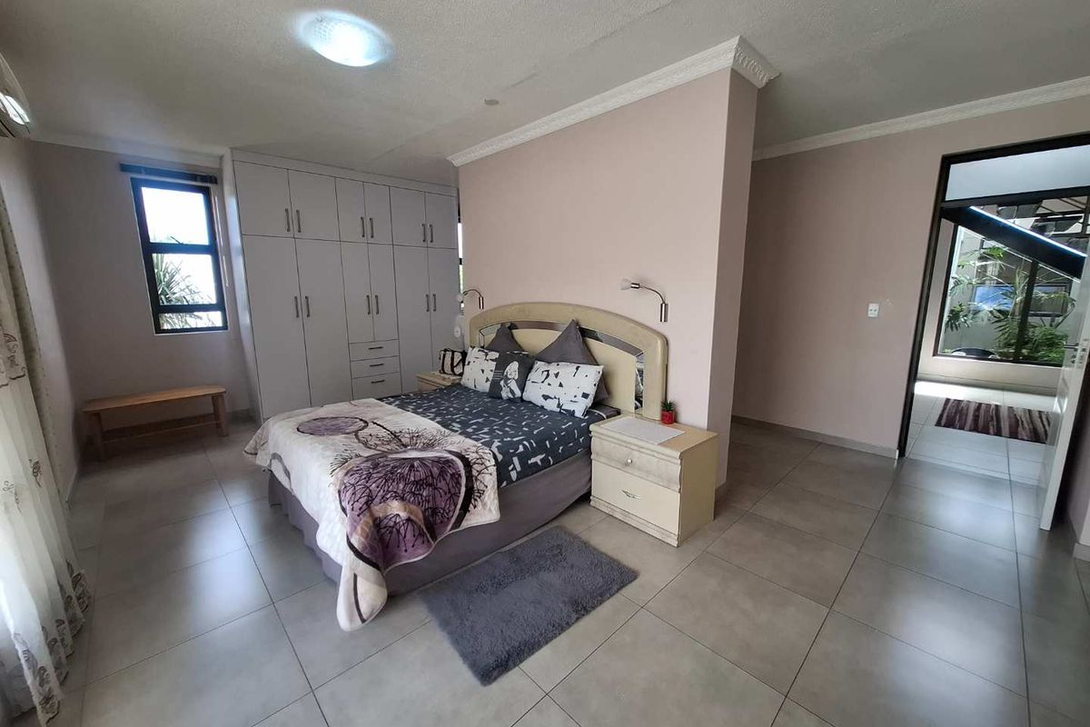 Spacious bedroom featuring built-in cupboards, tiled flooring, and a partition wall creating a distinct sleeping area with access to an adjoining space.