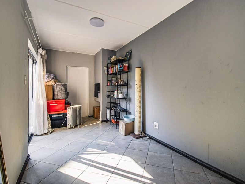 A living area featuring tiled flooring and a sliding glass door, currently used for storage with visible wall wear and cracking.