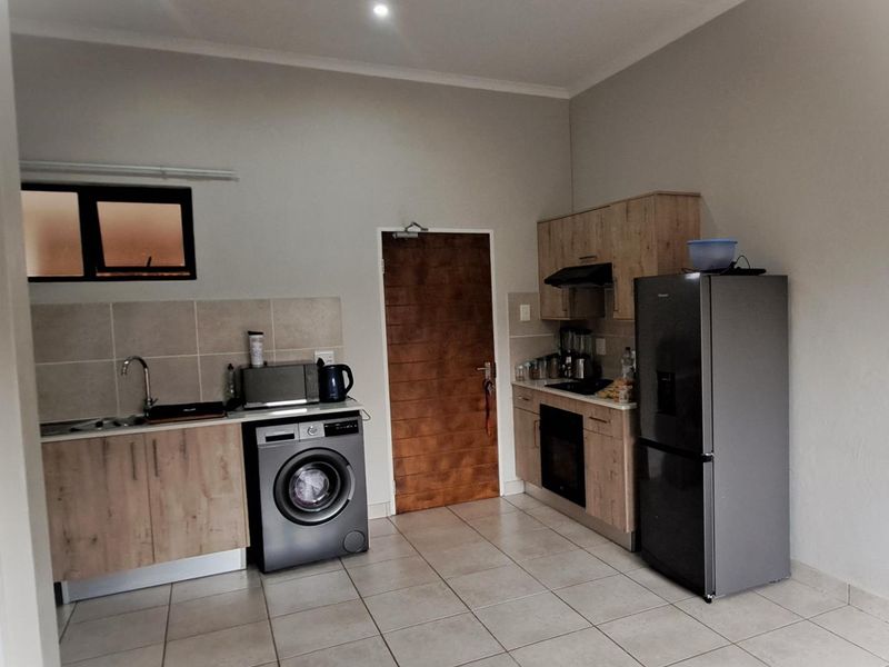 A functional kitchen featuring light wood-finish cabinetry, tiled flooring, a built-in oven with extractor fan, and a tiled backsplash.
