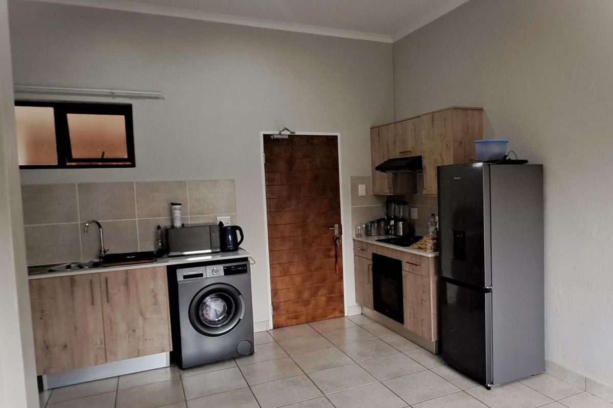 A functional kitchen featuring light wood-finish cabinetry, tiled flooring, a built-in oven with extractor fan, and a tiled backsplash.