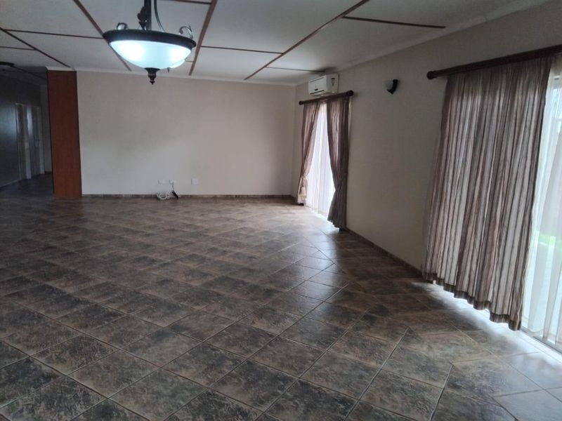 Spacious, empty living area featuring dark tiled flooring, a split-system air conditioner, and large sliding glass doors providing natural light.