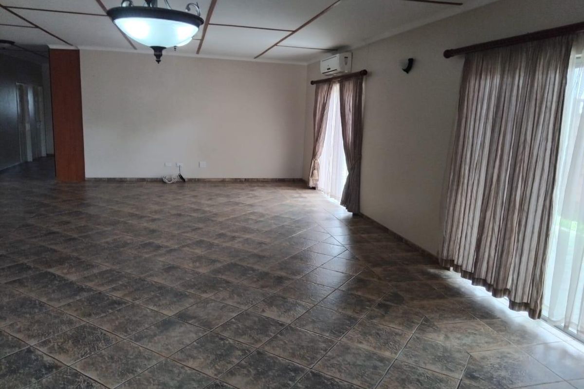 Spacious, empty living area featuring dark tiled flooring, a split-system air conditioner, and large sliding glass doors providing natural light.