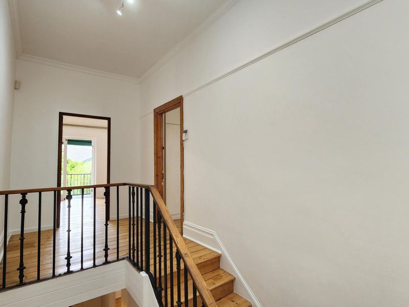 A bright and spacious landing area featuring timber flooring, a classic wrought iron balustrade, and traditional picture rails.