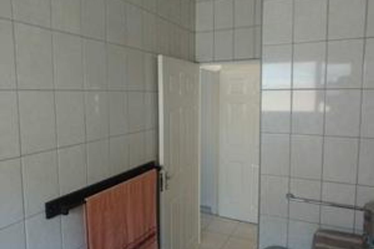 A functional bathroom space featuring full-height ceramic wall tiling and a neutral layout, ready for modernization or cosmetic updates.