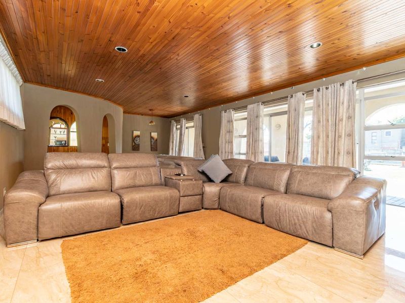 Spacious living room featuring a distinctive timber-clad vaulted ceiling, tiled flooring, and large sliding glass doors providing access to the outdoor area.