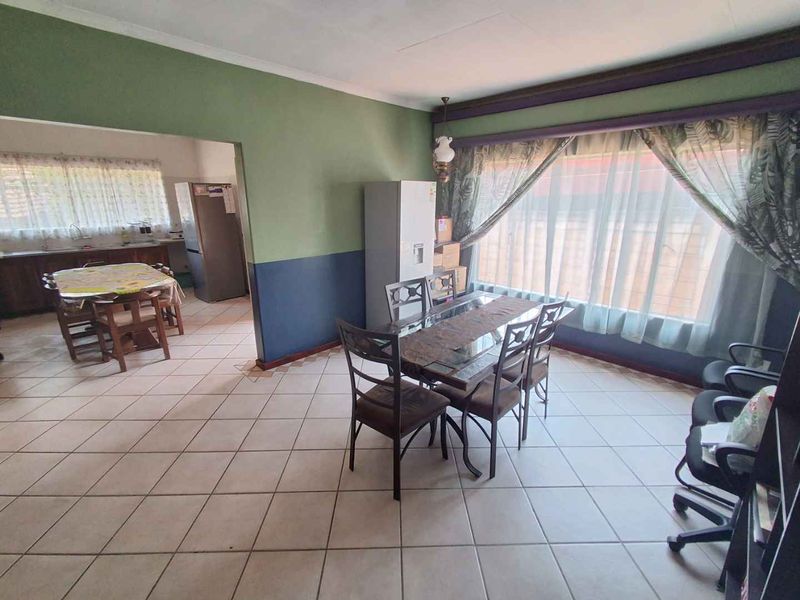 Open-plan dining area featuring tiled flooring and an archway leading to the kitchen, offering a functional layout with potential for modern updates.