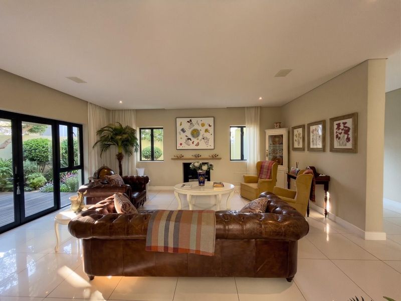 Spacious living room featuring tiled flooring, a central fireplace with a mantelpiece, and large glass sliding doors providing access to the garden.