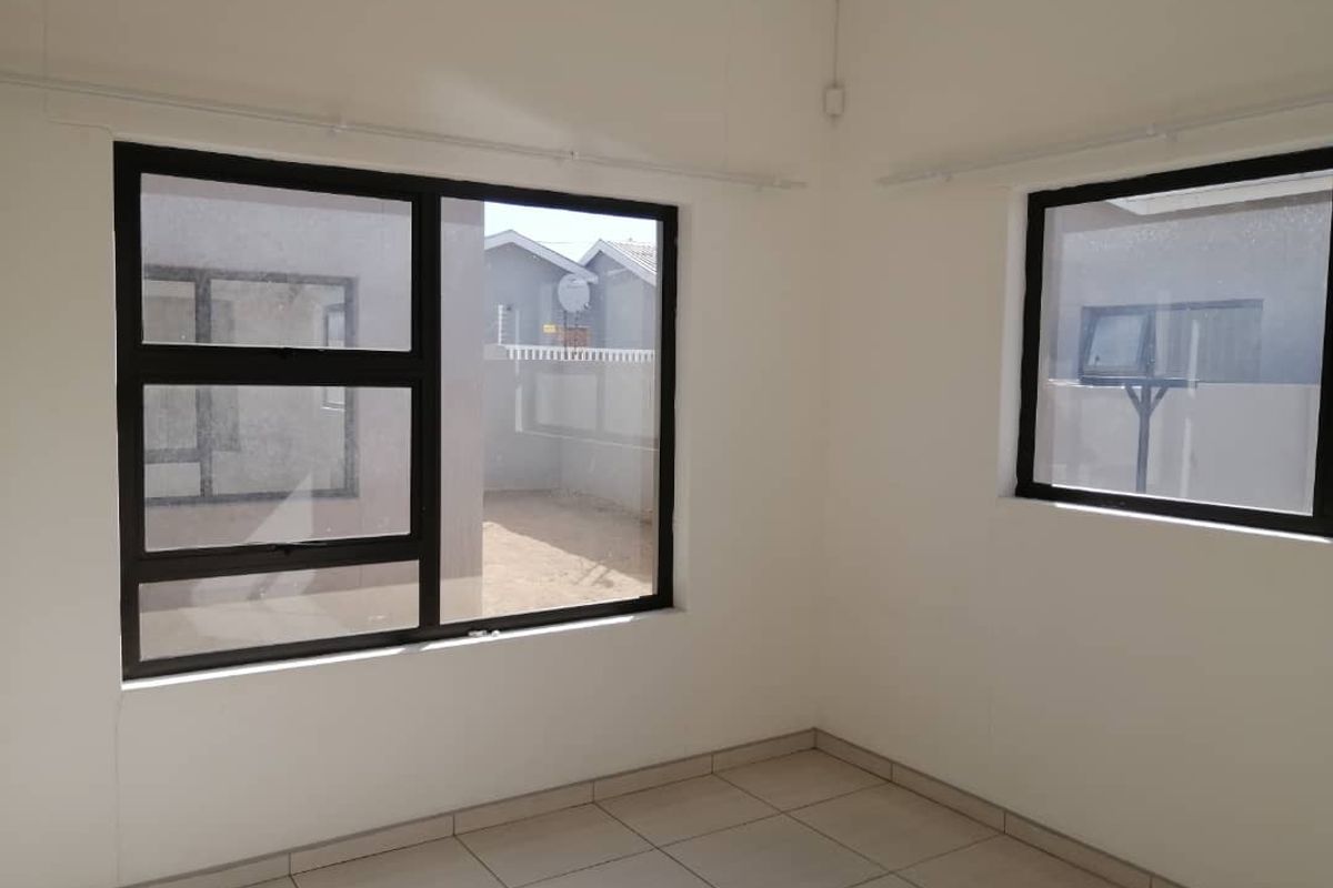 A bright, empty room featuring tiled flooring and black-framed windows, offering a clean and neutral space ready for personalization.