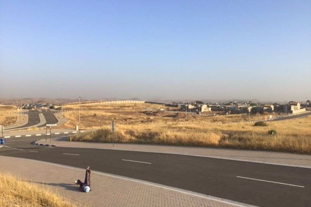 A view of a paved street and sidewalk in a developing commercial area with surrounding vacant land.