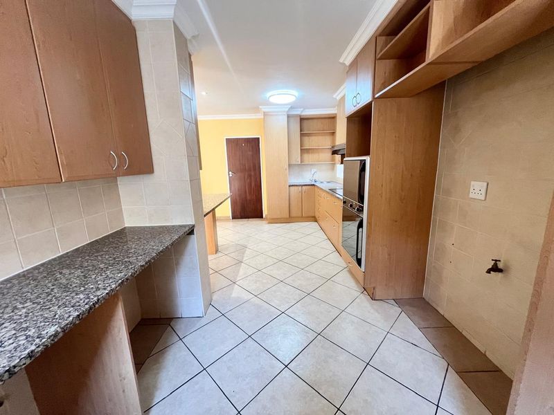 Spacious kitchen featuring built-in wooden cabinetry, granite countertops, tiled flooring, and integrated oven, offering a functional layout ready for modern updates.
