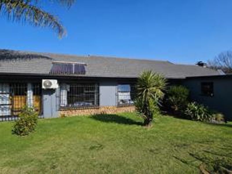 Rear view of the house featuring a tiled roof, solar water heating system, exterior air conditioning unit, and security bars on the windows.
