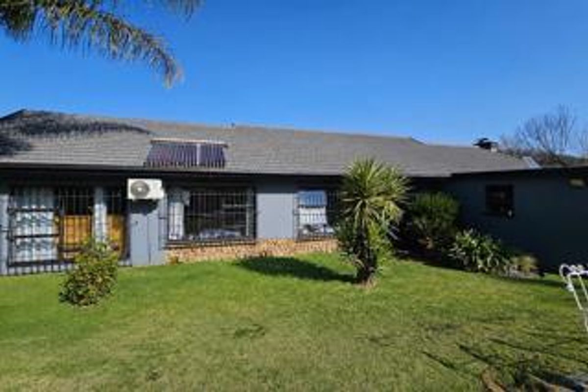 Rear view of the house featuring a tiled roof, solar water heating system, exterior air conditioning unit, and security bars on the windows.