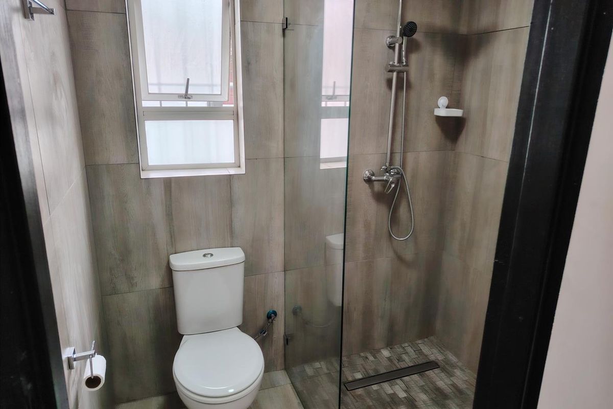 Modern bathroom featuring a walk-in shower with glass screen, tiled finishes, and a standard toilet.