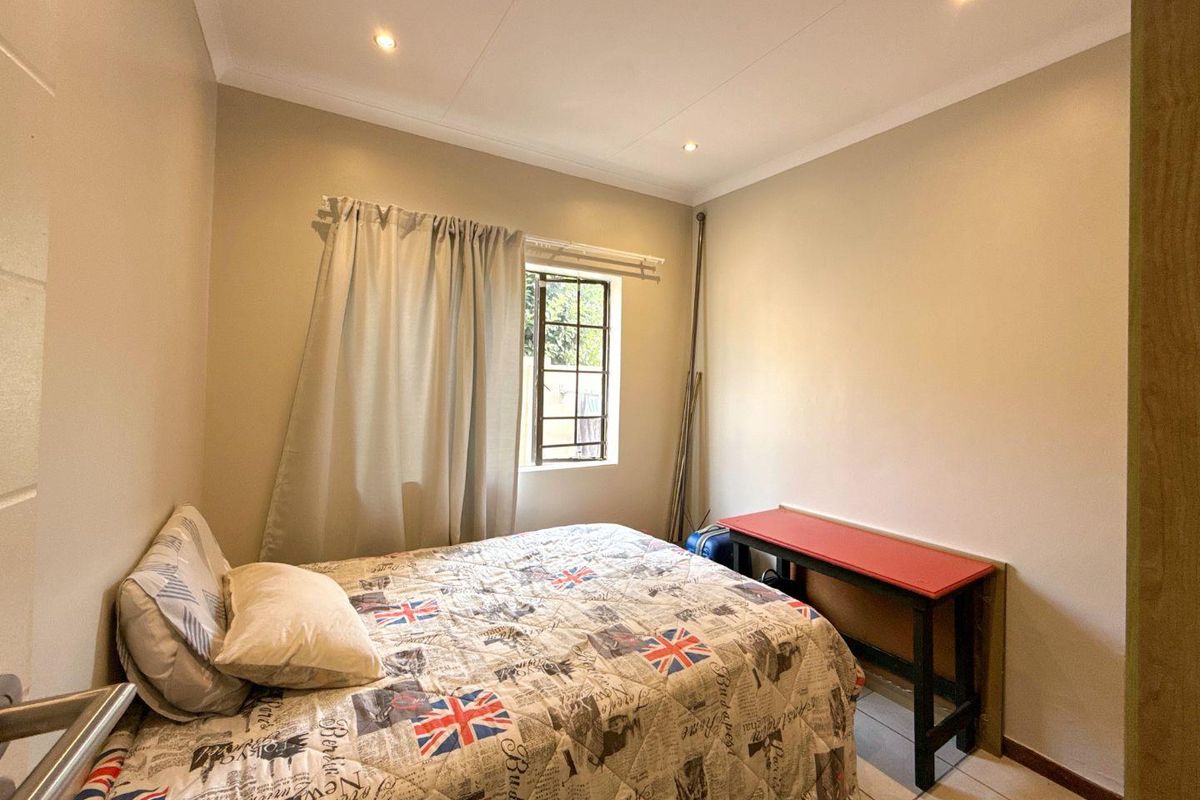 A standard bedroom featuring tiled flooring, recessed ceiling lighting, and a window with security bars.