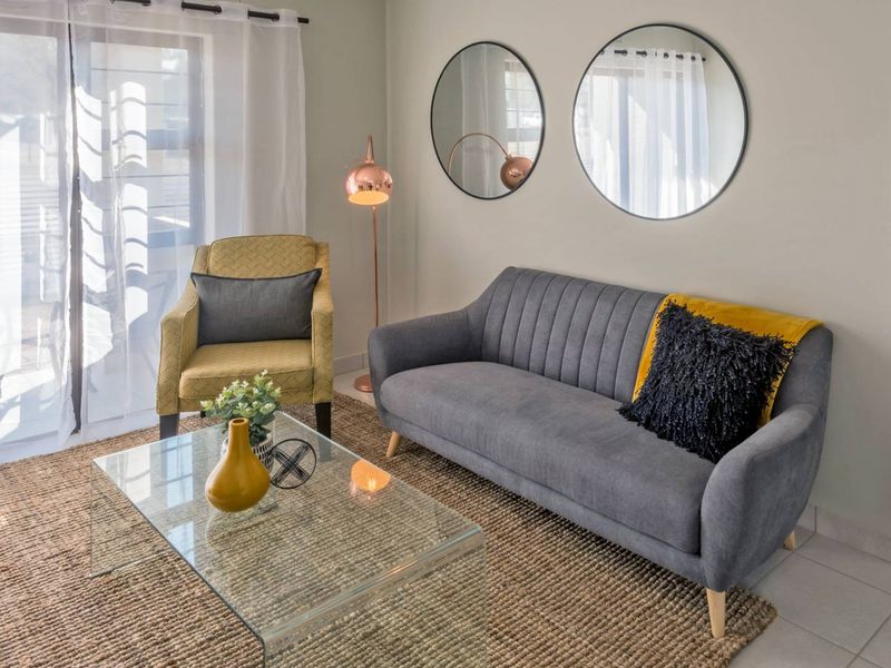 A bright and well-maintained living room featuring tiled flooring and a large sliding glass door providing natural light.