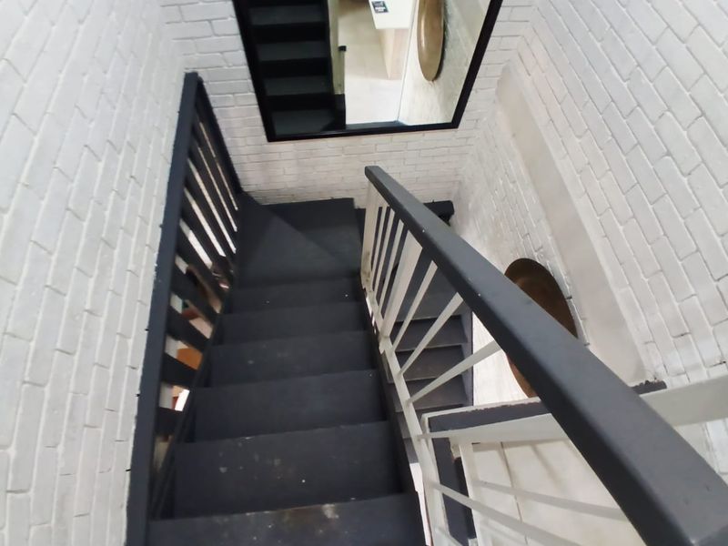 A staircase featuring painted brick walls and a dark-toned balustrade, providing a modern industrial aesthetic to the home's circulation space.