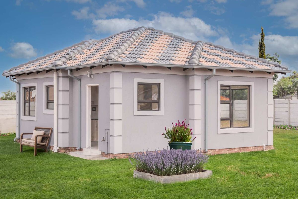 A well-maintained detached dwelling featuring a tiled roof, plastered exterior walls, and aluminium window frames, set within a neat garden.