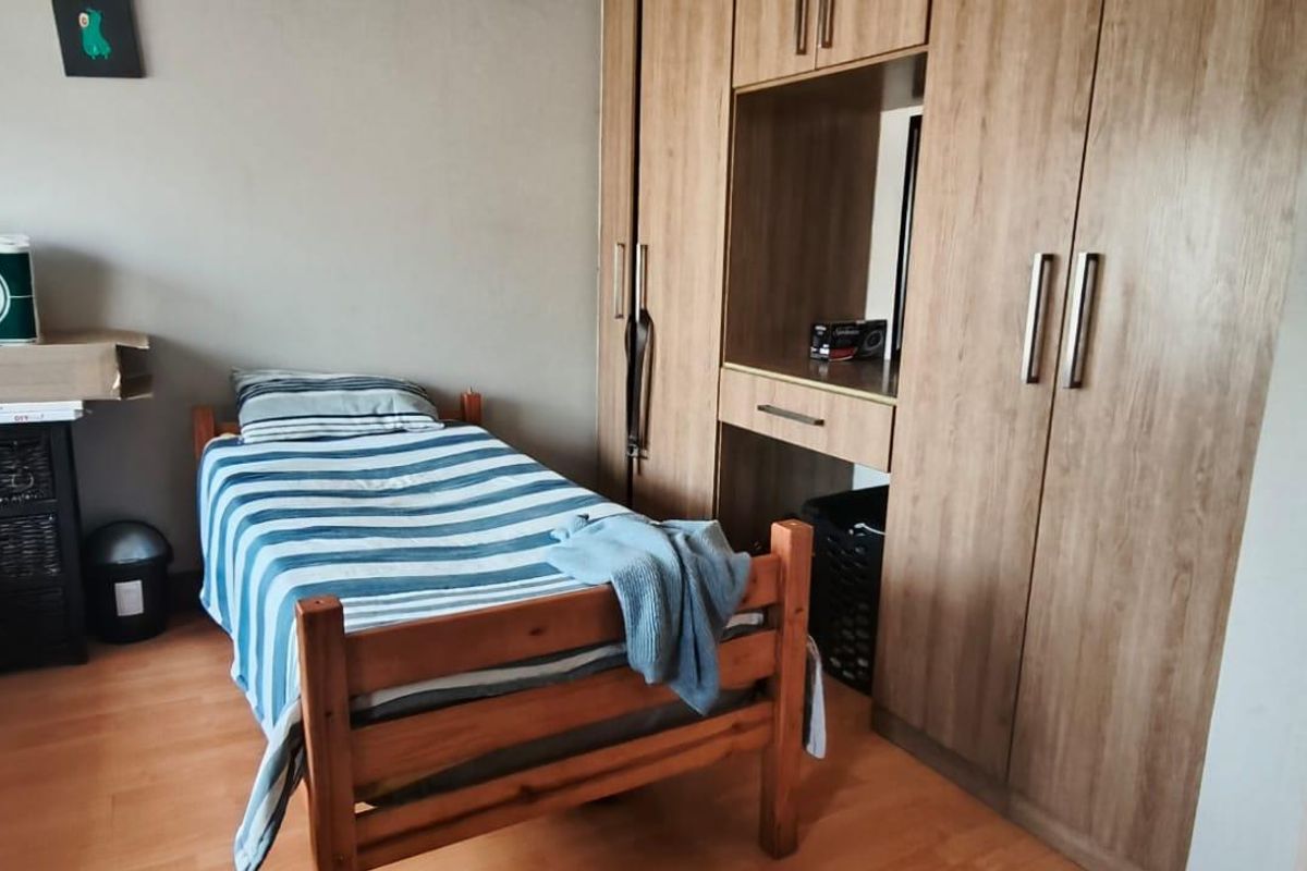 A bedroom featuring built-in wooden cabinetry with integrated shelving and laminate flooring.