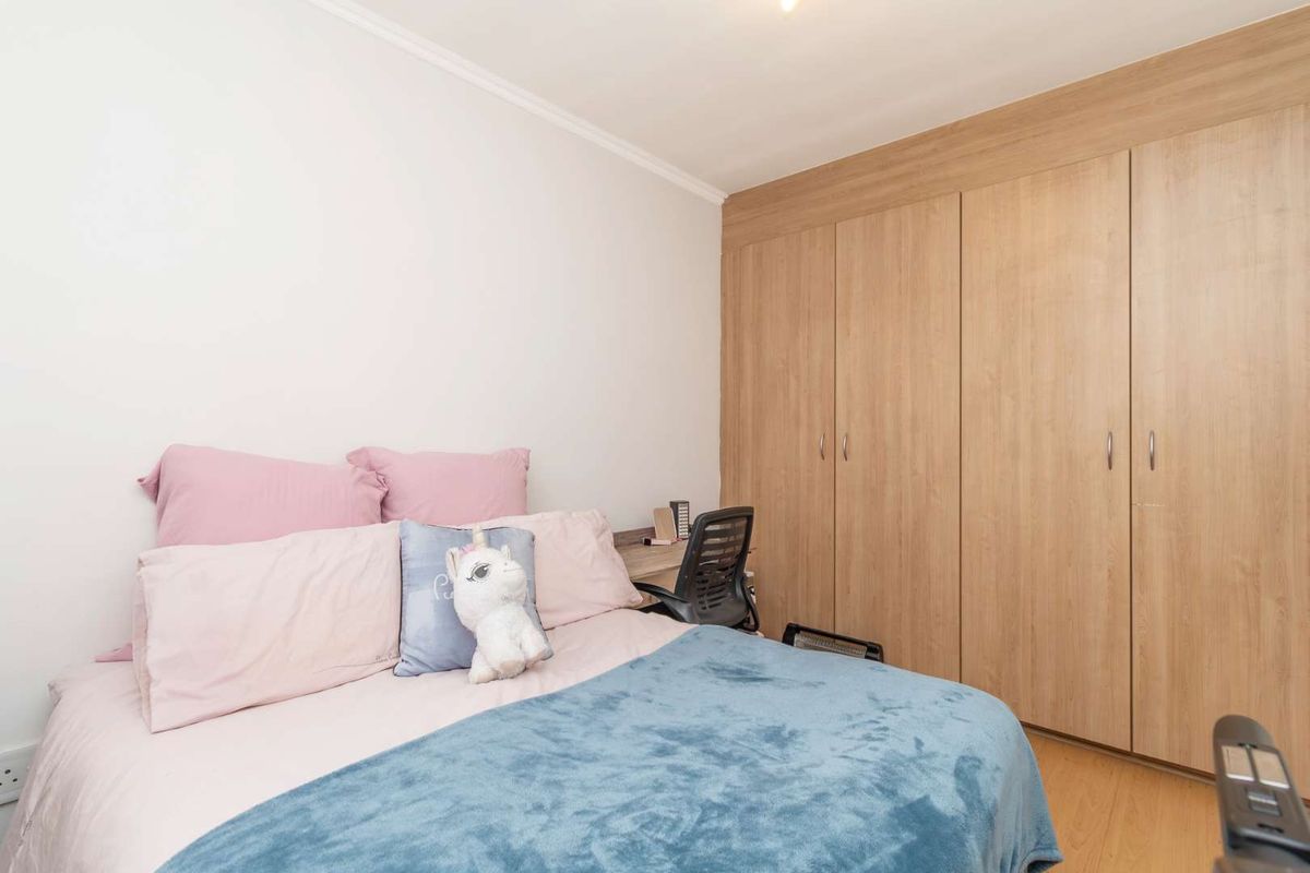 A well-maintained bedroom featuring light wood-look laminate flooring and integrated floor-to-ceiling wooden cabinetry for ample storage.